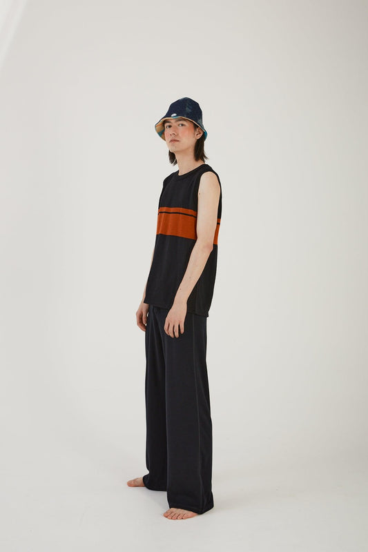 A person wearing merino wool track pants, a merino wool striped vest and an upcycled wool blanket and denim hat